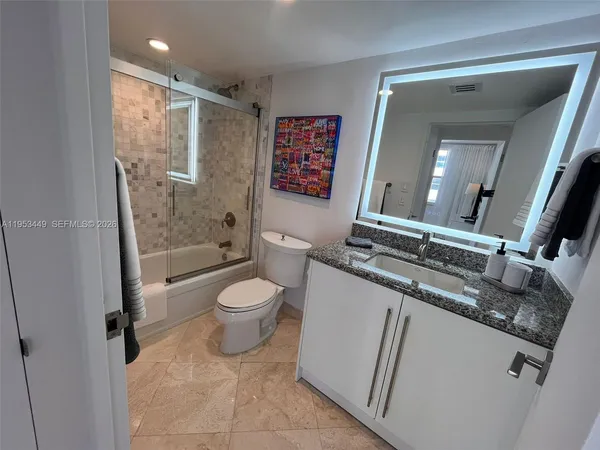 a bathroom with a granite countertop sink toilet and shower