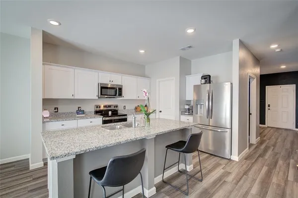 a kitchen with granite countertop a refrigerator and microwave