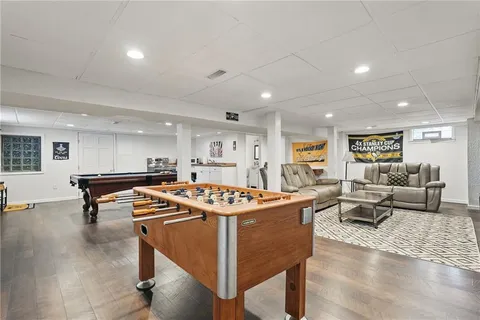 a living room with furniture pool table and a wooden floor