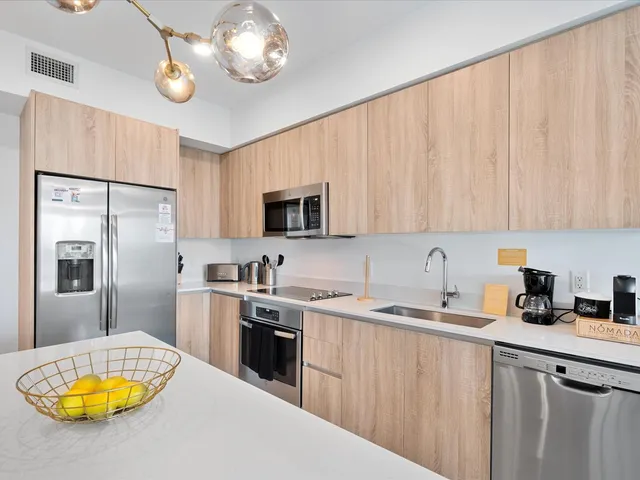 a kitchen with a sink a stove a refrigerator cabinets and a dining table