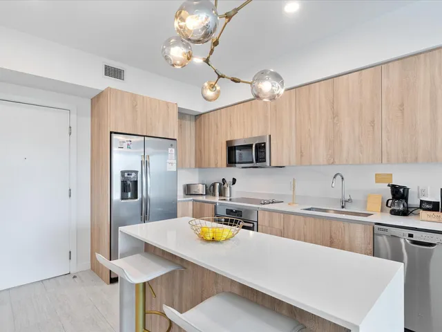 a kitchen with stainless steel appliances a white table chairs refrigerator and cabinets