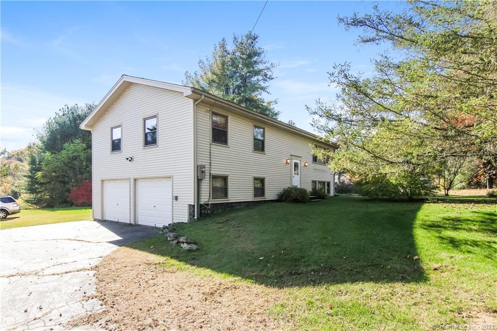 a view of a white house next to a yard with big trees