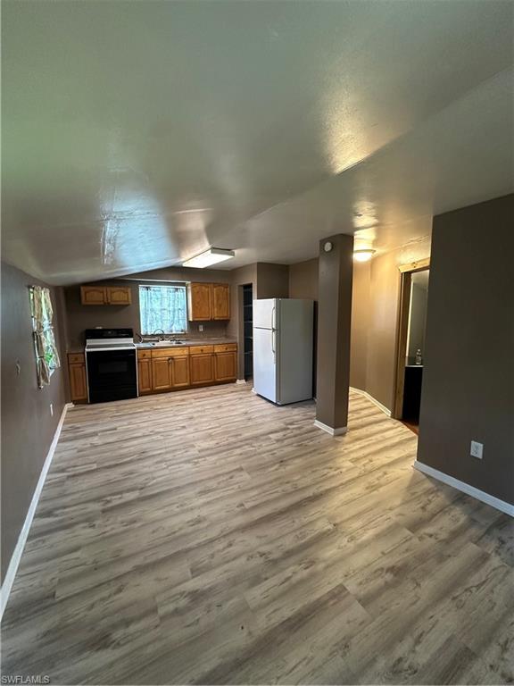 a view of empty room with a kitchen and refrigerator