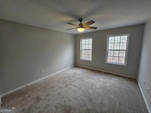 an empty room with windows and chandelier fan
