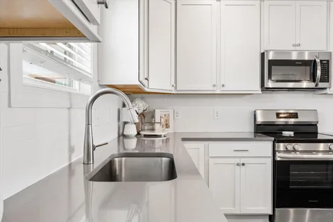 a kitchen with granite countertop a stove a sink and a microwave