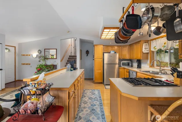 a kitchen with stainless steel appliances granite countertop a stove a dining table and chairs with wooden floor