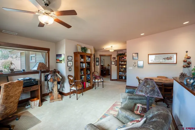 a living room with furniture a ceiling fan and a book shelf