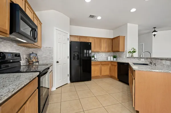 a kitchen with stainless steel appliances kitchen island granite countertop a sink a stove top oven a refrigerator and dishwasher