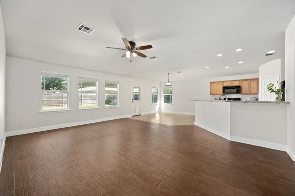 a view of an empty room with window and wooden floor