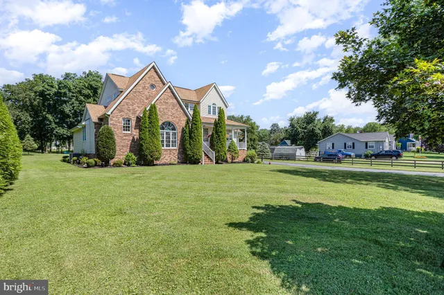 a front view of a house with garden and trees