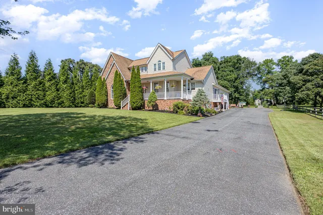 a view of a white house with a big yard and large trees