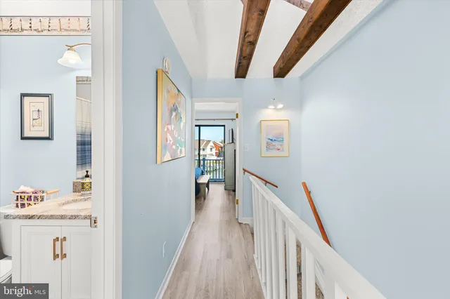 a view of a hallway to a livingroom with wooden floor and stairs