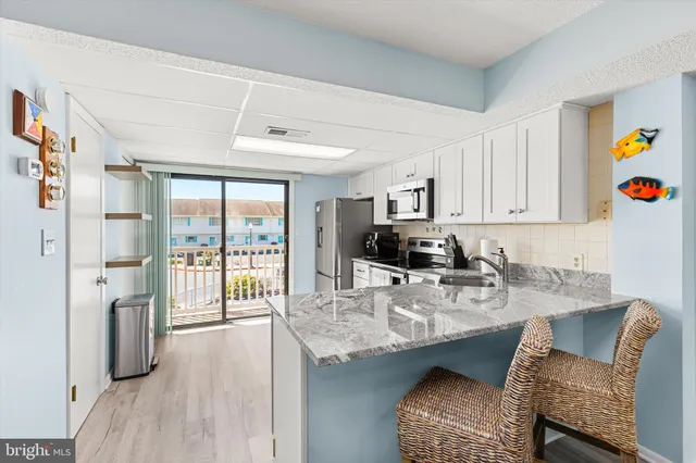 a kitchen with stainless steel appliances granite countertop a stove a refrigerator a sink dishwasher a dining table and chairs with wooden floor