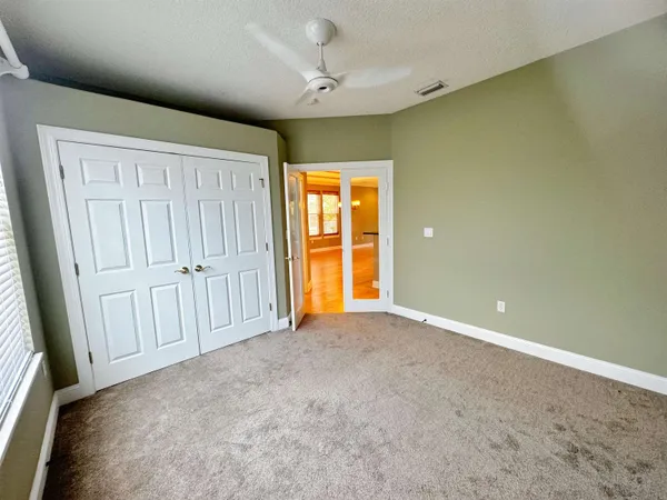 an empty room with windows and a ceiling fan