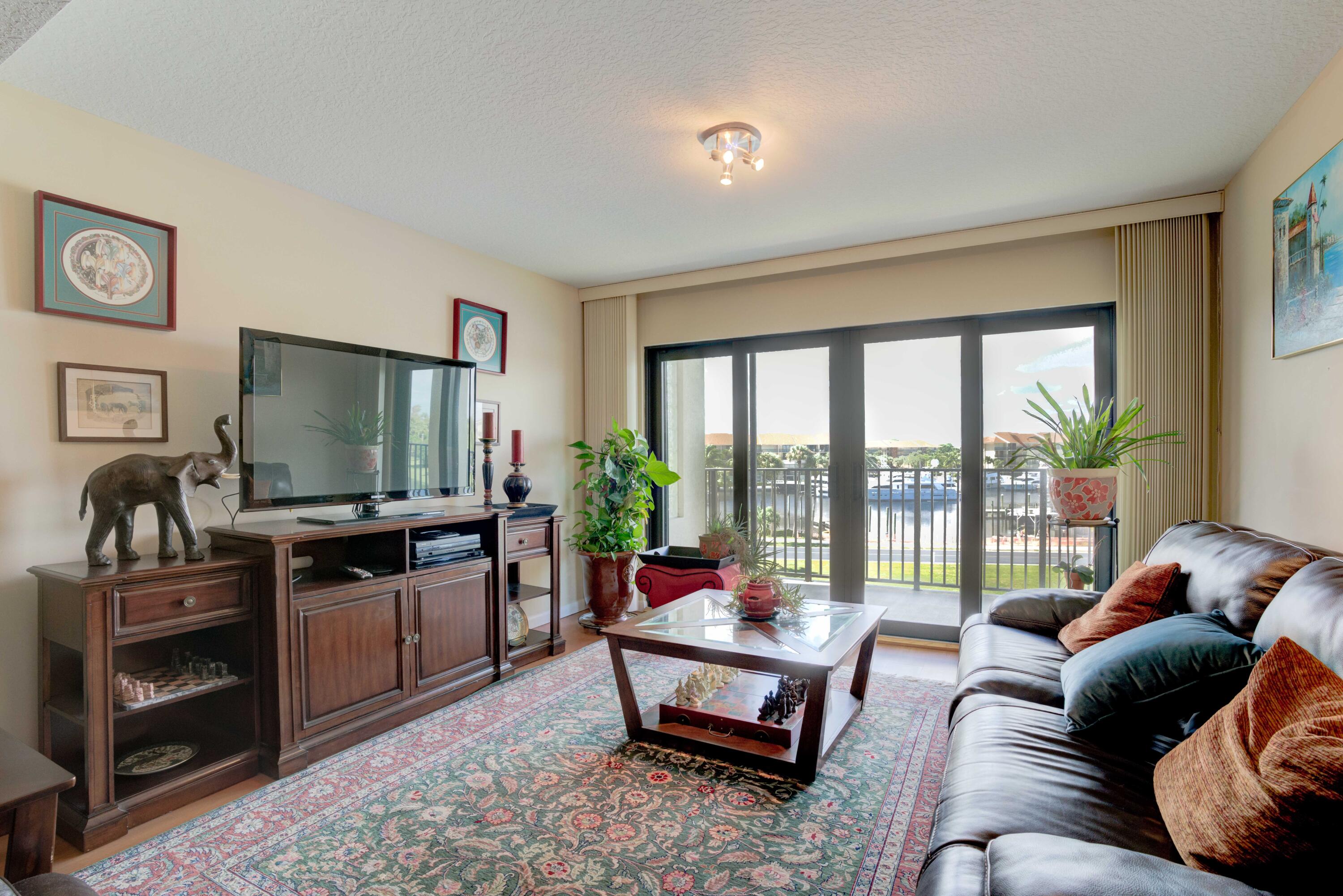 801 Seafarer Circle, Unit 404 Jupiter, FL 33477 - Photo 24 of 34 a living room with furniture a flat screen tv and floor to ceiling window