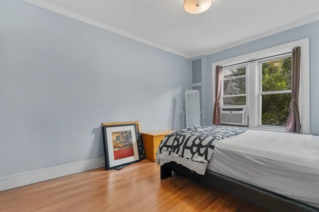 a bedroom with a bed and a window with chair