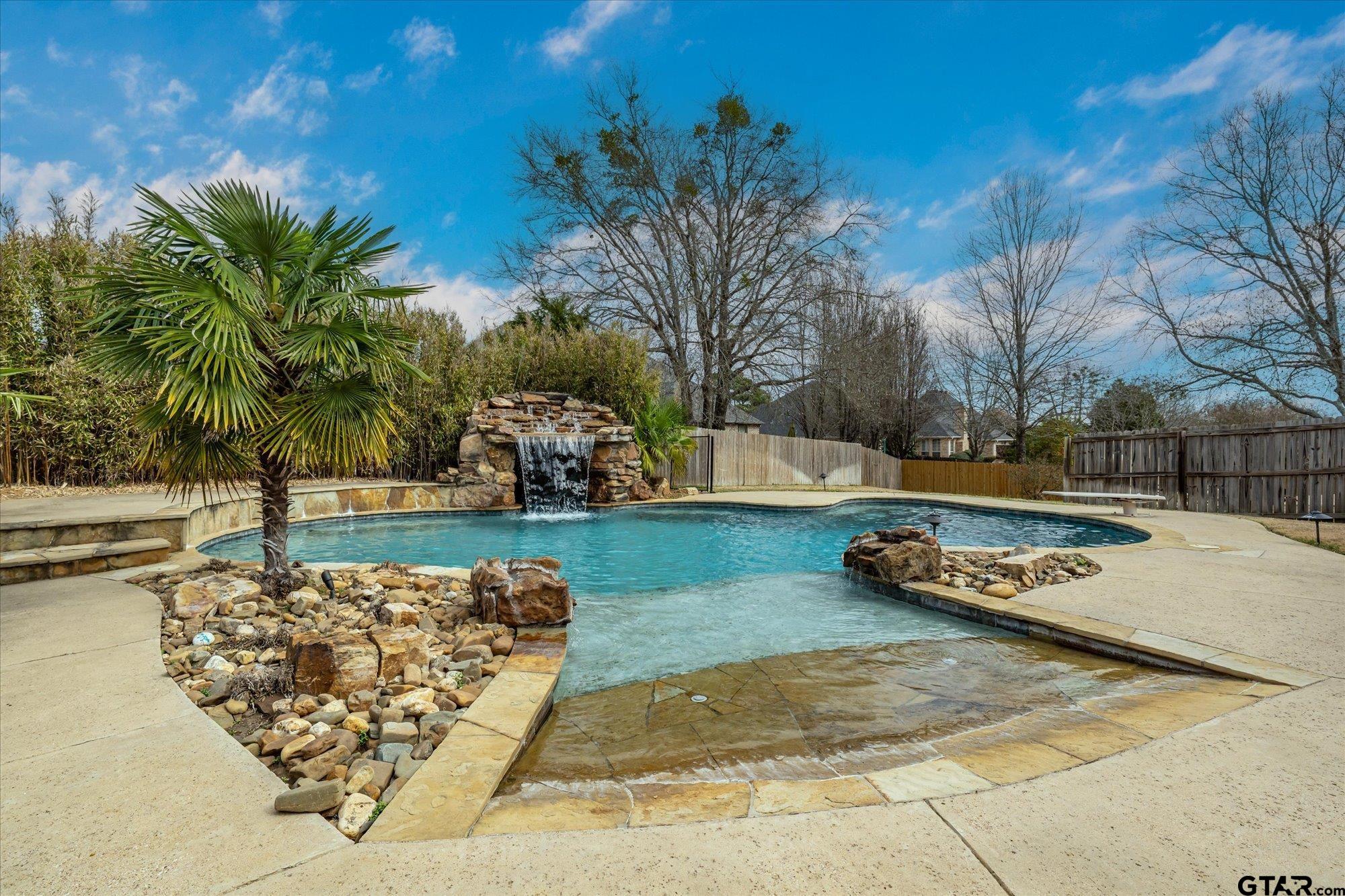 Swimming pool features a heater, grotto with sitting areas, walk-in shallow end, and a diving board.