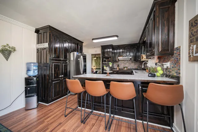 a kitchen with stainless steel appliances a dining table chairs and wooden floor