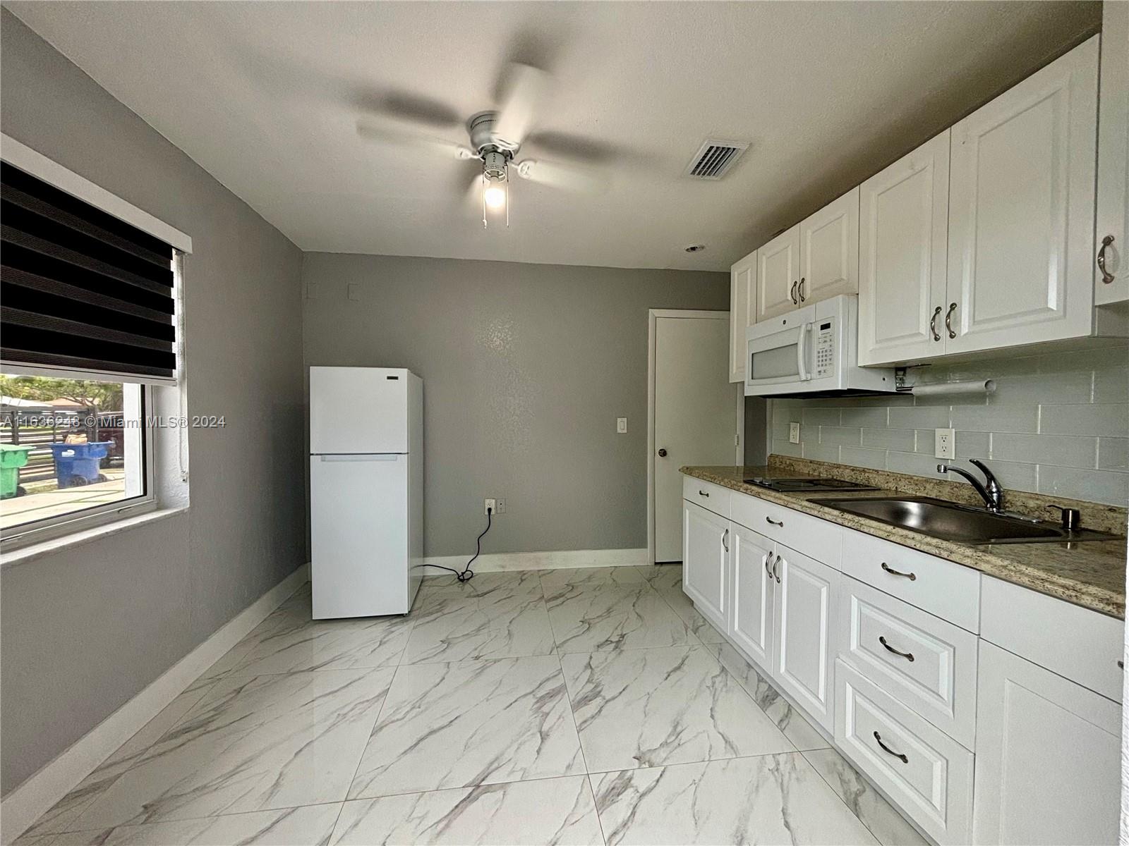 11001 Southwest 56th Street, Unit 2 Miami, FL 33165 - Photo 5 of 10 a kitchen with granite countertop a stove a sink and a refrigerator