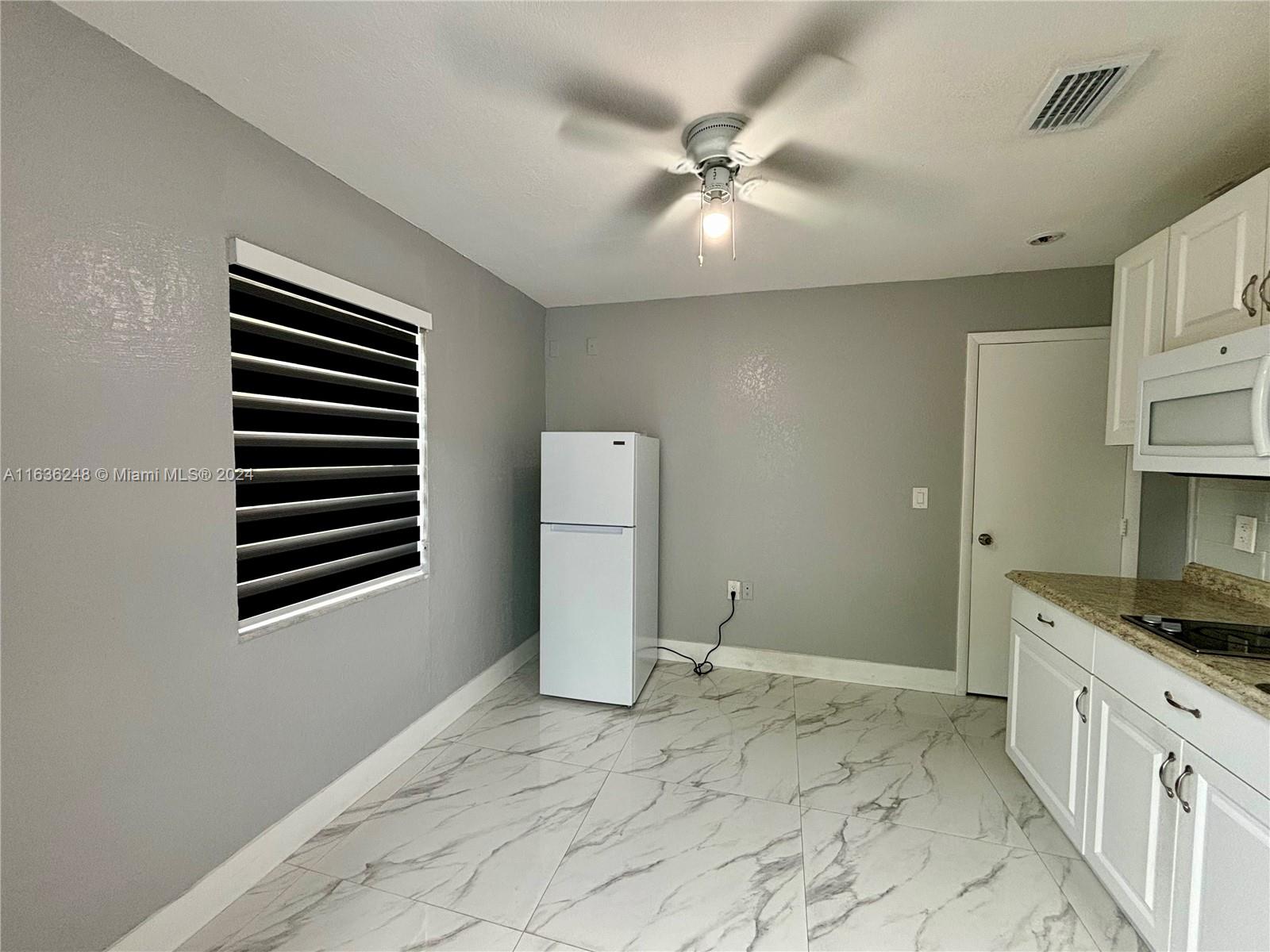 11001 Southwest 56th Street, Unit 2 Miami, FL 33165 - Photo 6 of 10 a kitchen with a refrigerator and white cabinets