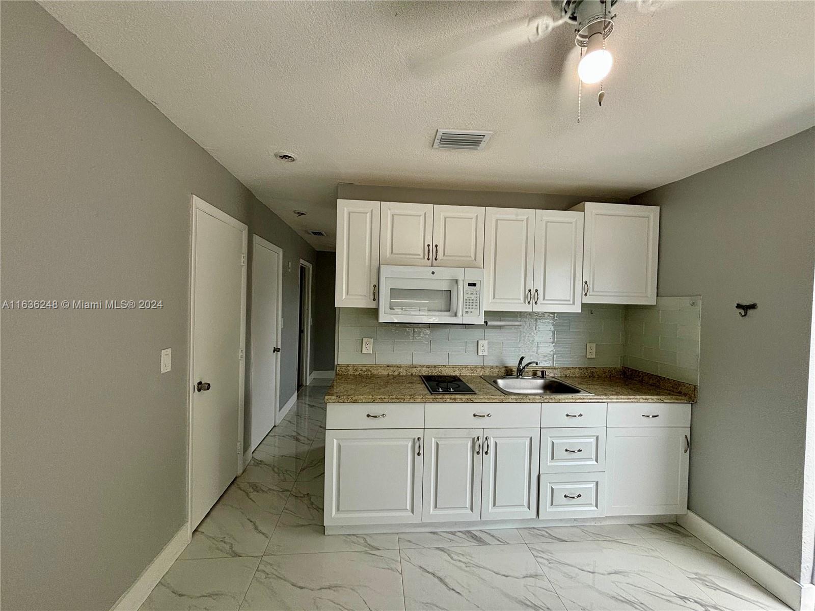 11001 Southwest 56th Street, Unit 2 Miami, FL 33165 - Photo 7 of 10 a kitchen with granite countertop a sink cabinets and refrigerator