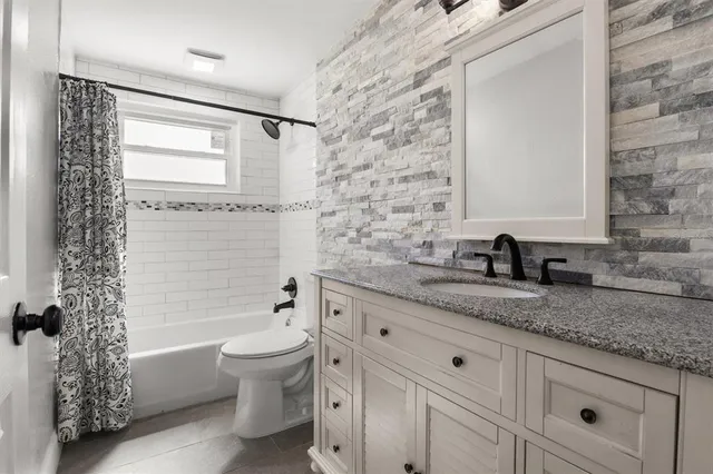 a bathroom with a granite countertop sink a toilet and shower
