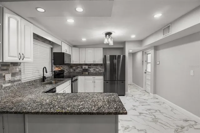 a kitchen with stainless steel appliances granite countertop a sink refrigerator and microwave