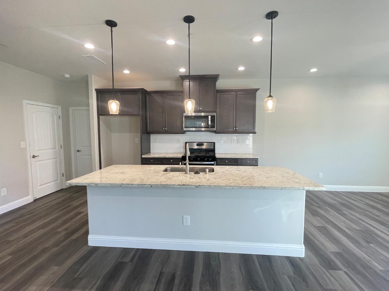 105 South Walnut Avenue Kerman, CA 93630 - Photo 3 of 22 a large kitchen with kitchen island a stove a sink a center island and wooden floor