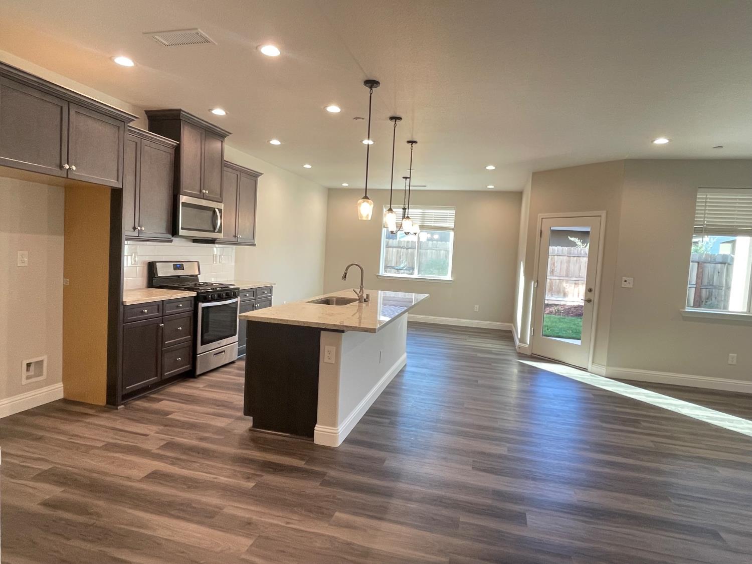 105 South Walnut Avenue Kerman, CA 93630 - Photo 5 of 22 a large kitchen with stainless steel appliances kitchen island a large counter top and wooden floors