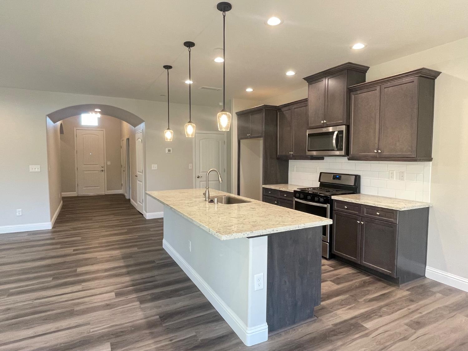 105 South Walnut Avenue Kerman, CA 93630 - Photo 6 of 22 a large kitchen with stainless steel appliances kitchen island granite countertop a stove a sink a refrigerator and a wooden cabinets