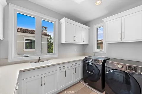 a utility room with stainless steel appliances granite countertop a sink a washer and dryer