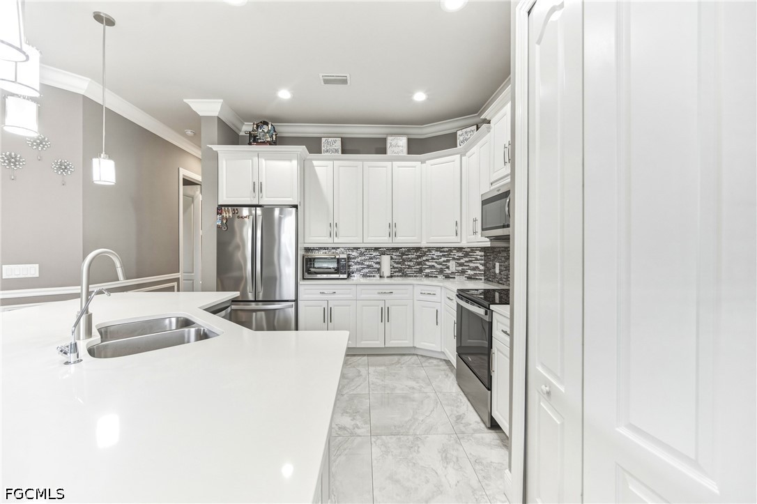 1700 43rd Terrace Southwest Naples, FL 34116 - Photo 22 of 38 a kitchen with white cabinets and stainless steel appliances