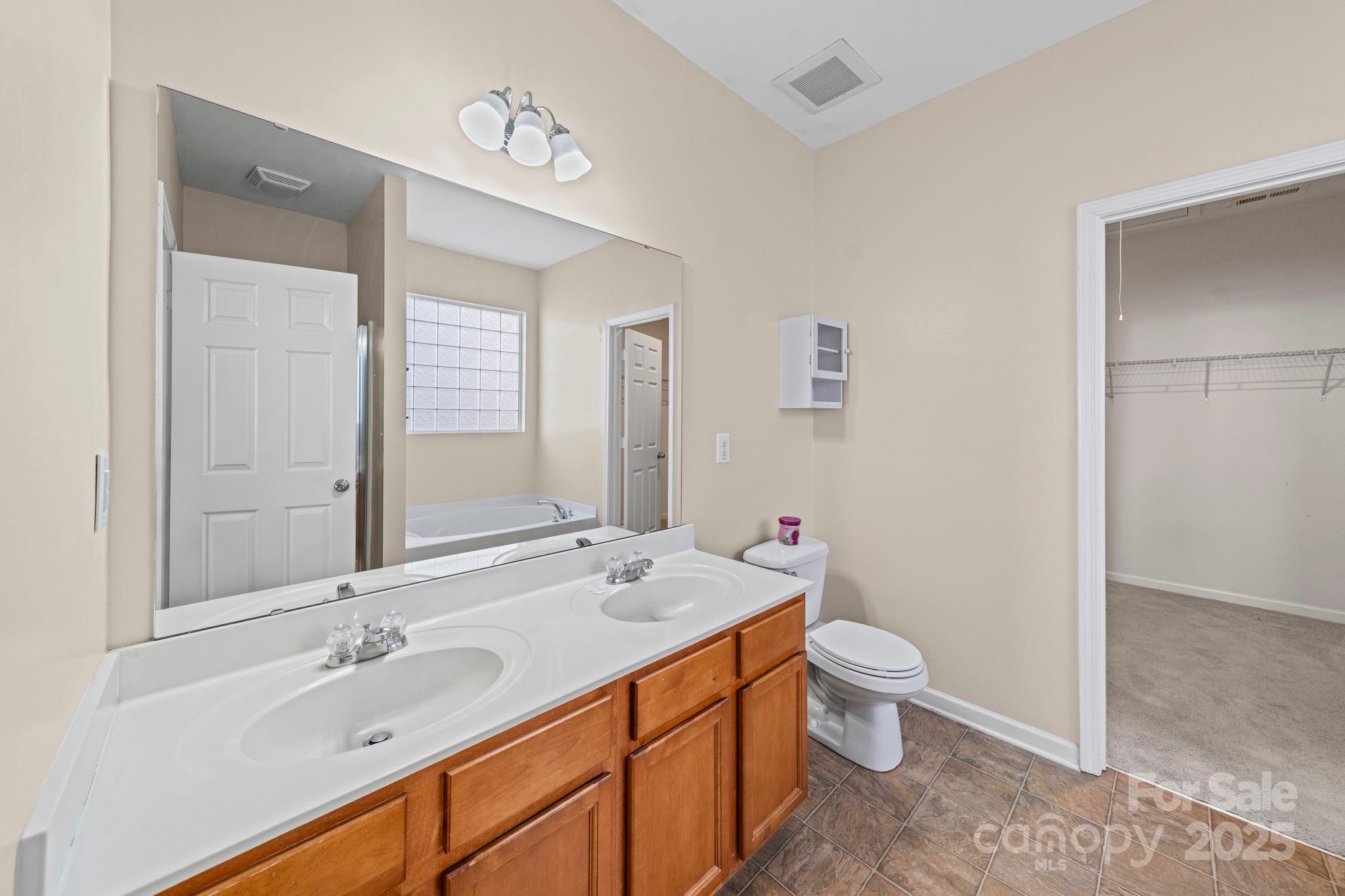 11608 Downy Birch Road Charlotte, NC 28227 - Photo 30 of 38 a spacious bathroom with a double vanity sink toilet mirror and shower
