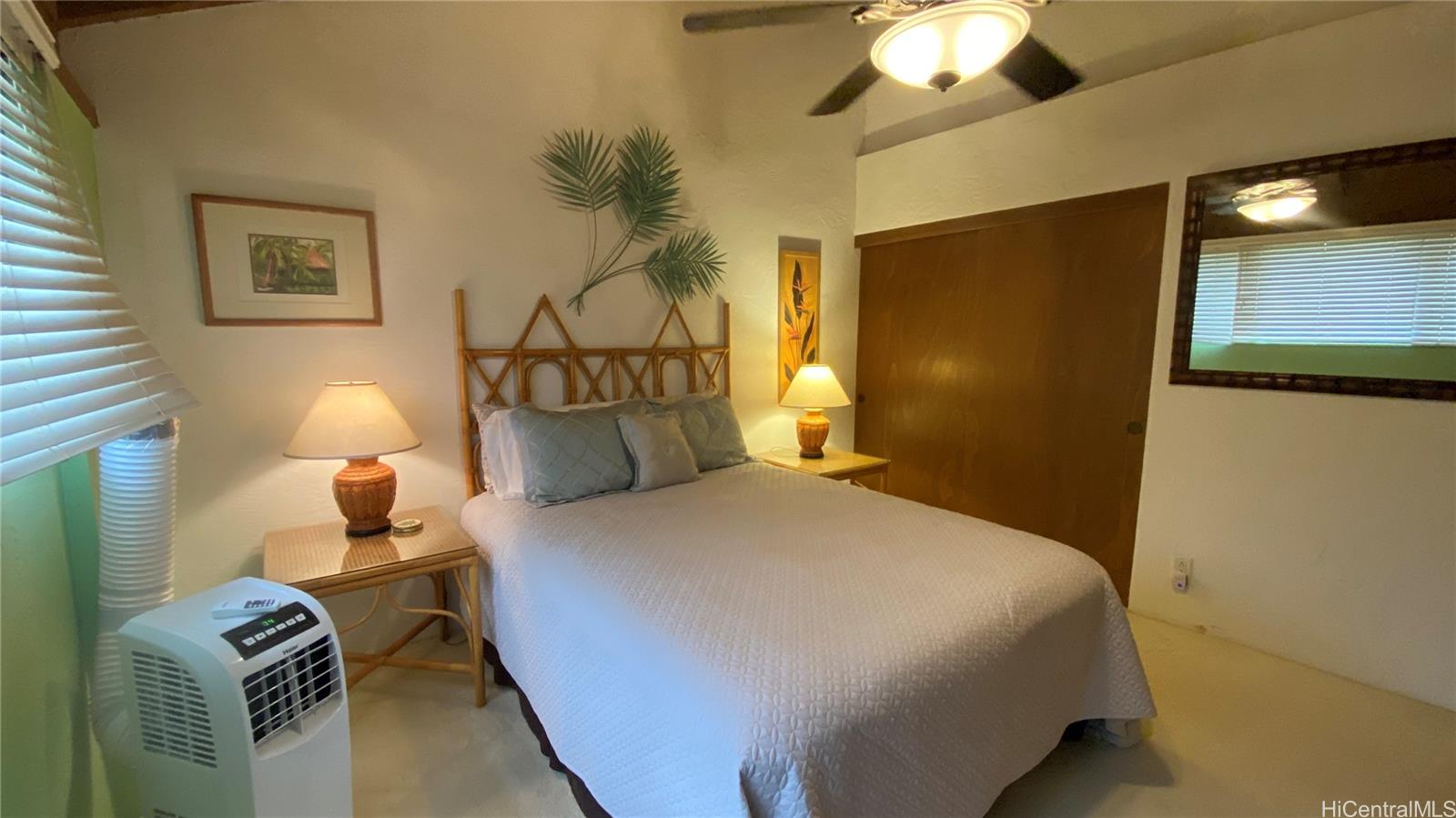 68-3840 Lua Kula Street, Unit E202 Waikoloa, HI 96738 - Photo 15 of 25 a bedroom with a bed and a chandelier