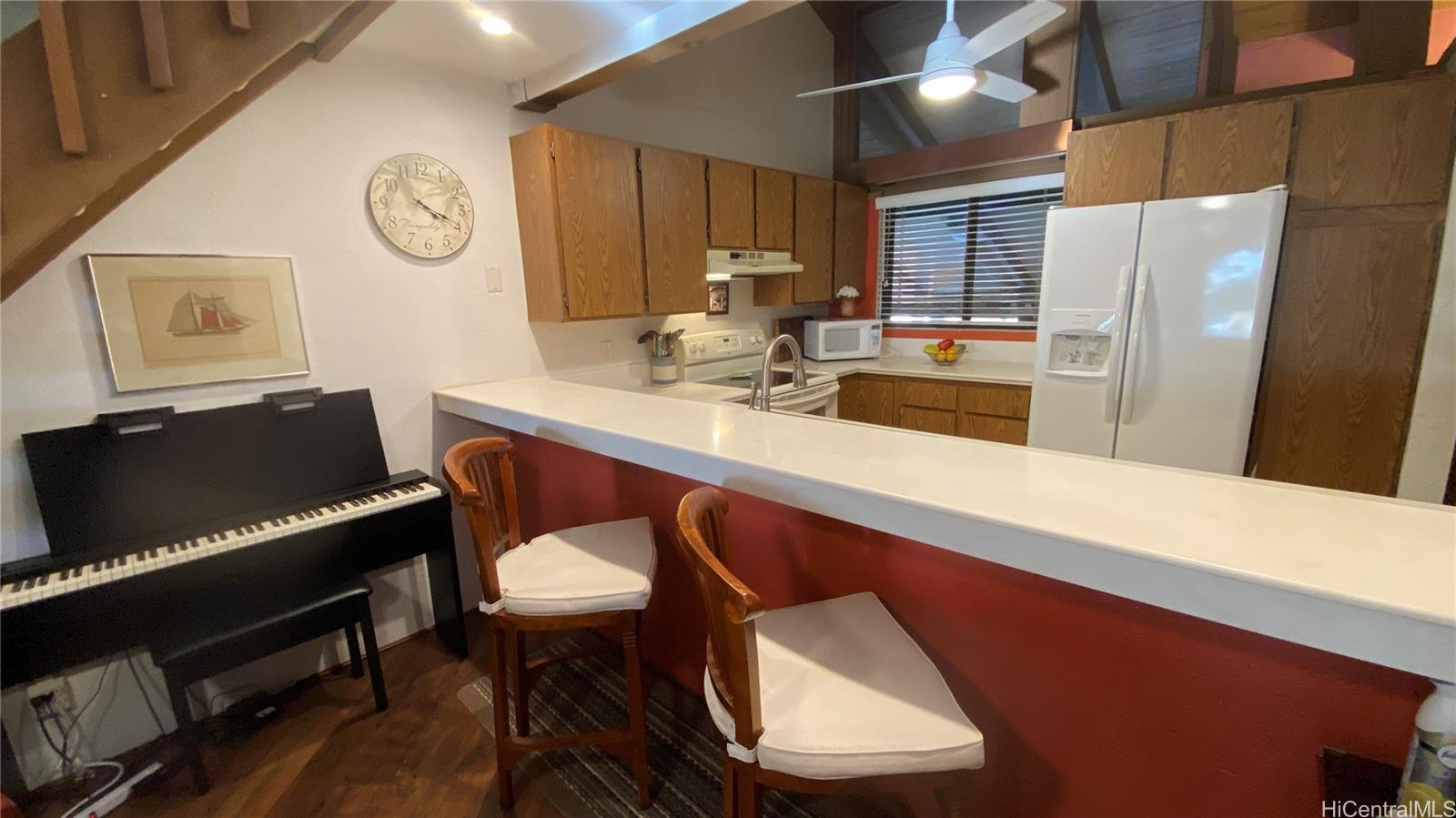 68-3840 Lua Kula Street, Unit E202 Waikoloa, HI 96738 - Photo 5 of 25 a kitchen with stainless steel appliances a table chairs and a refrigerator