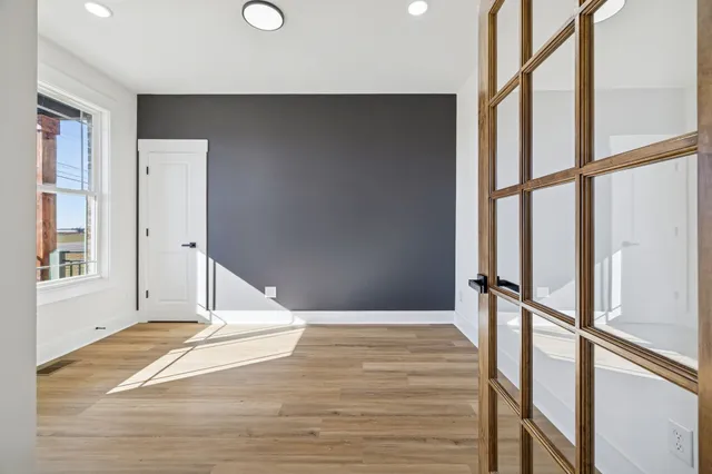 a view of an empty room with wooden floor and a window