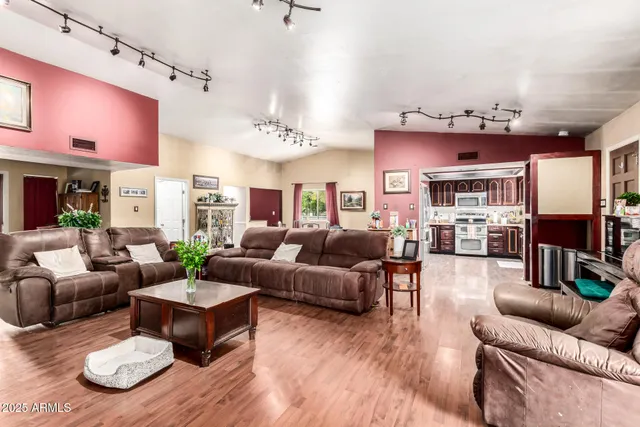 a living room with furniture kitchen view and a wooden floor