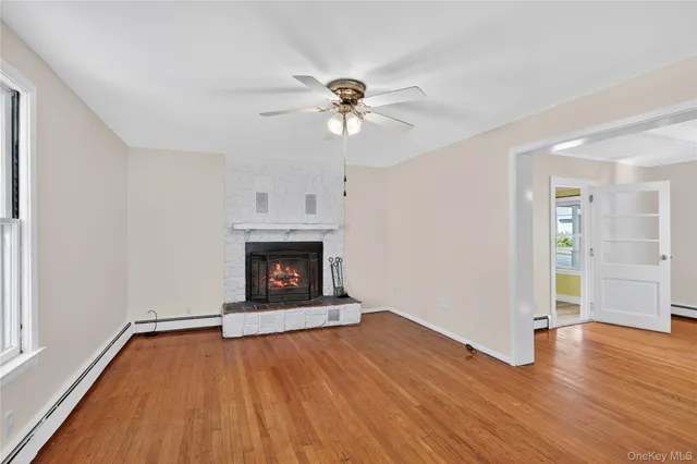 an empty room with wooden floor a chandelier fan and a fireplace