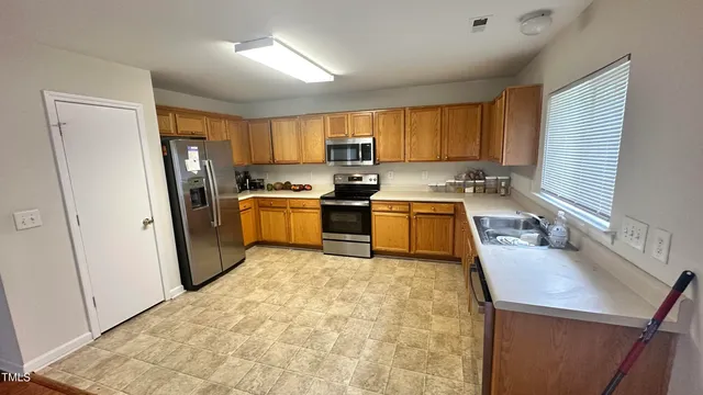 a kitchen with a sink a stove a refrigerator cabinets and a window