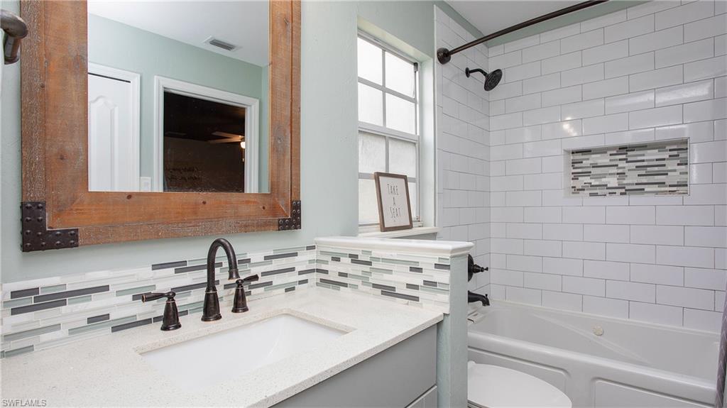 17269 Lee Road Fort Myers, FL 33967 - Photo 11 of 26 Full bathroom with tasteful backsplash, tiled shower / bath combo, vanity, and toilet