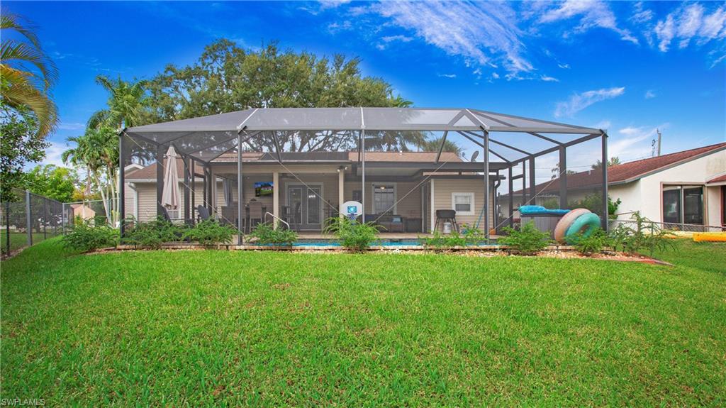 17269 Lee Road Fort Myers, FL 33967 - Photo 23 of 26 Rear view of property with a lawn, glass enclosure, and a patio area