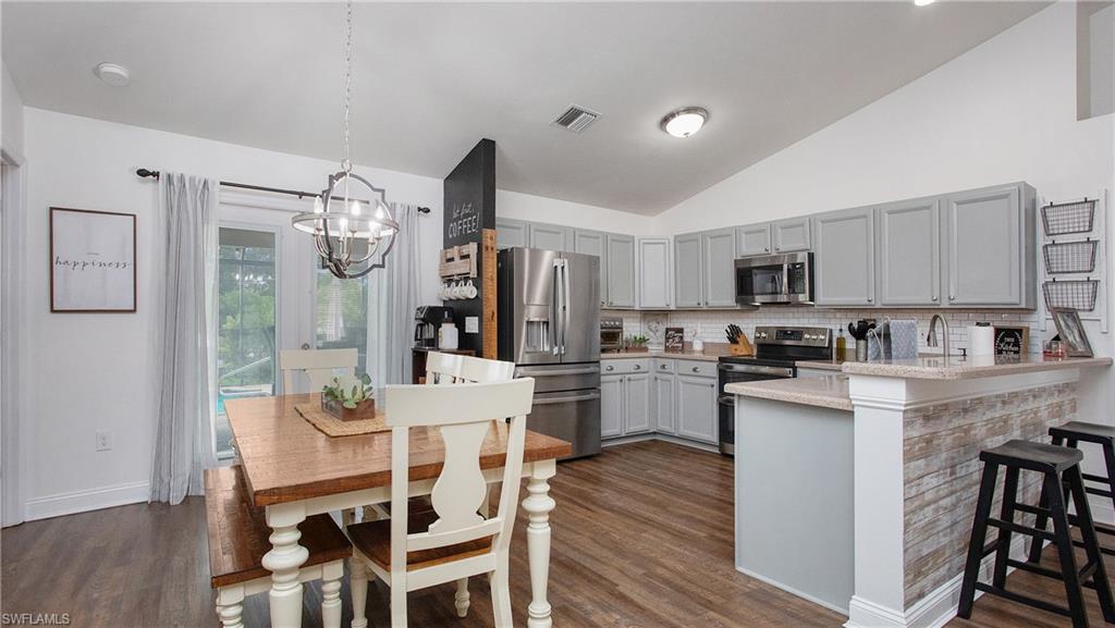17269 Lee Road Fort Myers, FL 33967 - Photo 7 of 26 Kitchen with pendant lighting, a breakfast bar, a chandelier, kitchen peninsula, and stainless steel appliances