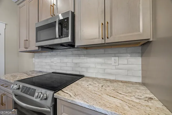 a kitchen with stainless steel appliances granite countertop a table chairs stove and refrigerator