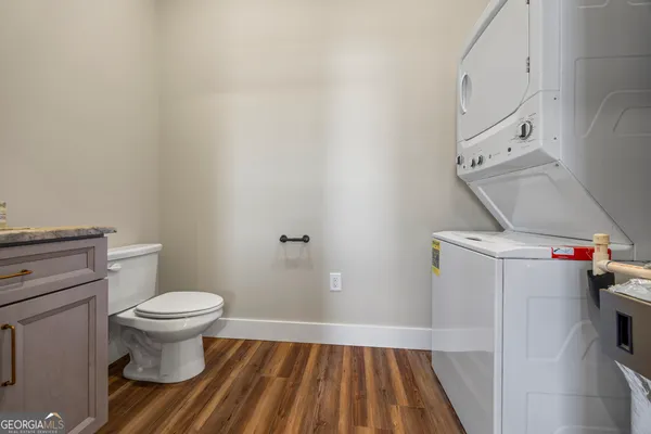 a view of a hallway with wooden floor and a bathroom