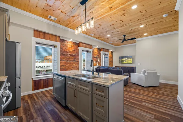 a dining hall with stainless steel appliances granite countertop a sink and wooden floor