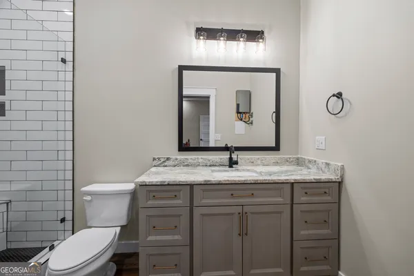 a bathroom with a granite countertop sink a toilet and shower