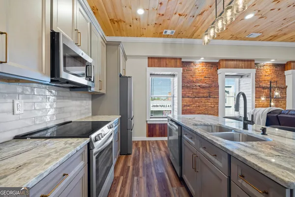 a kitchen with stainless steel appliances granite countertop a sink a stove and a wooden floors