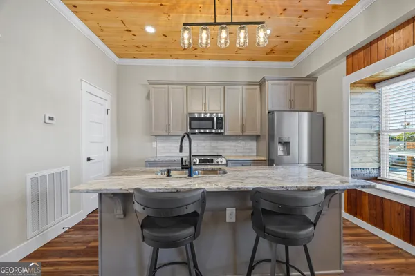 a kitchen with stainless steel appliances granite countertop a sink a stove a refrigerator cabinets and chairs