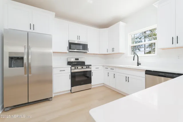 a kitchen with white cabinets and appliances