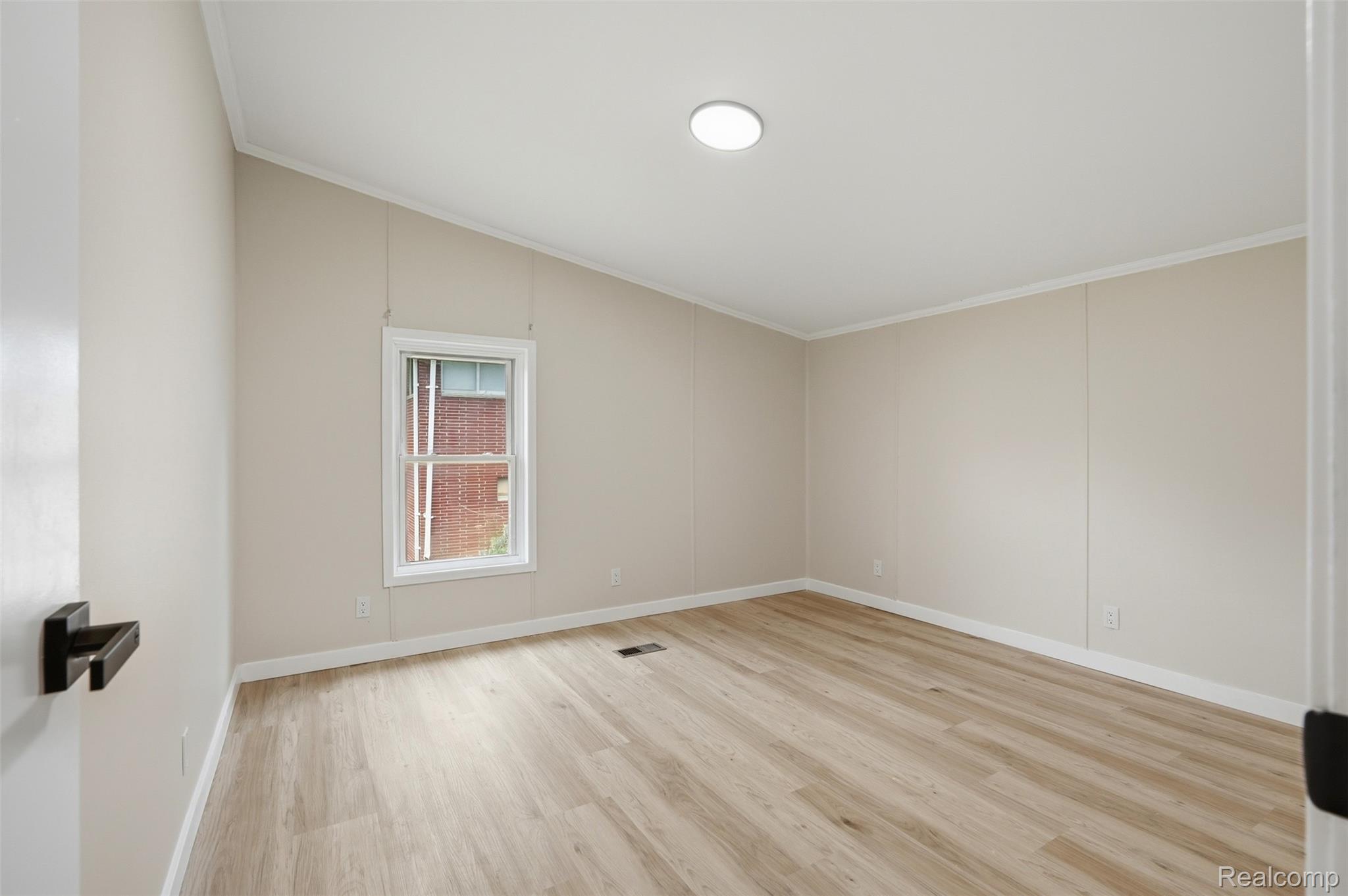 4420 Dublin Road Burton, MI 48529 - Photo 24 of 56 Room featuring wood-finish flooring, neutral wall panels, white trim, a single window, and a flush-mount ceiling light